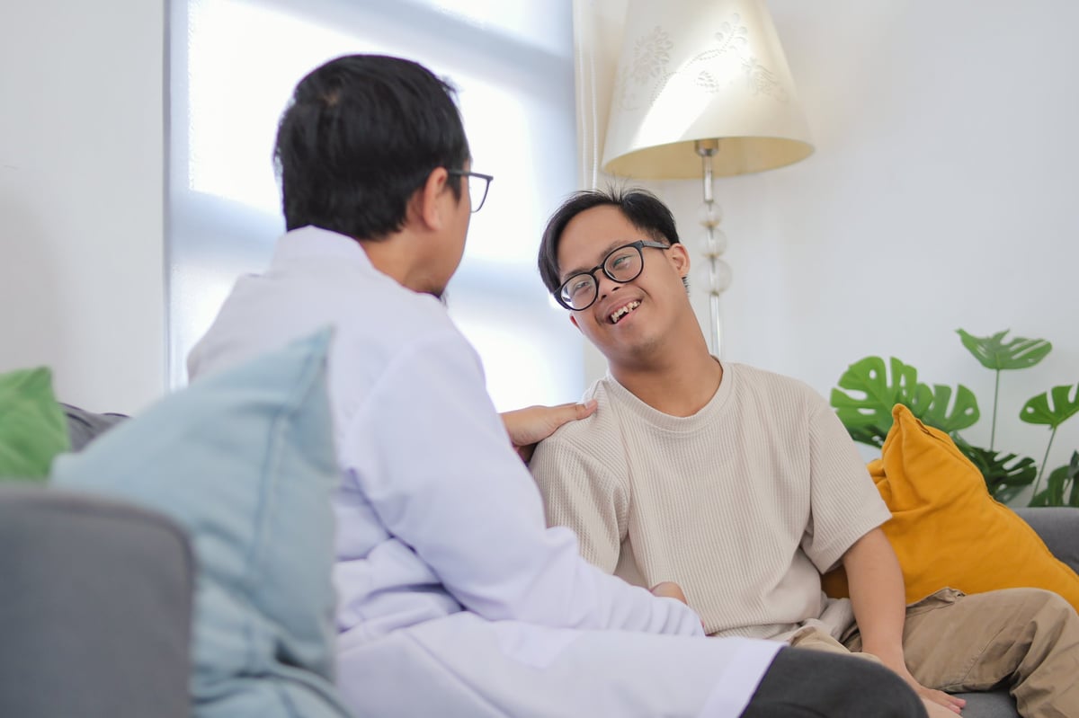 Carer talking with a young disabled person in a supportive home assessment conversation